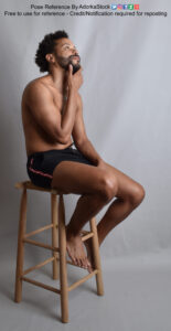 Pose reference model sitting on a stool, touching his face as if thinking