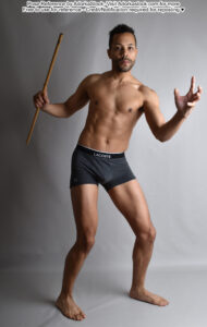 Latino model standing with a magic wand and an open hand as if casting a spell