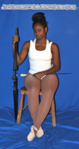 Black female pose reference model sitting a chair with a bow in hand and an arrow across her lap