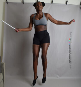 thin black female model in hovering pose with one arm out the other holding a wand