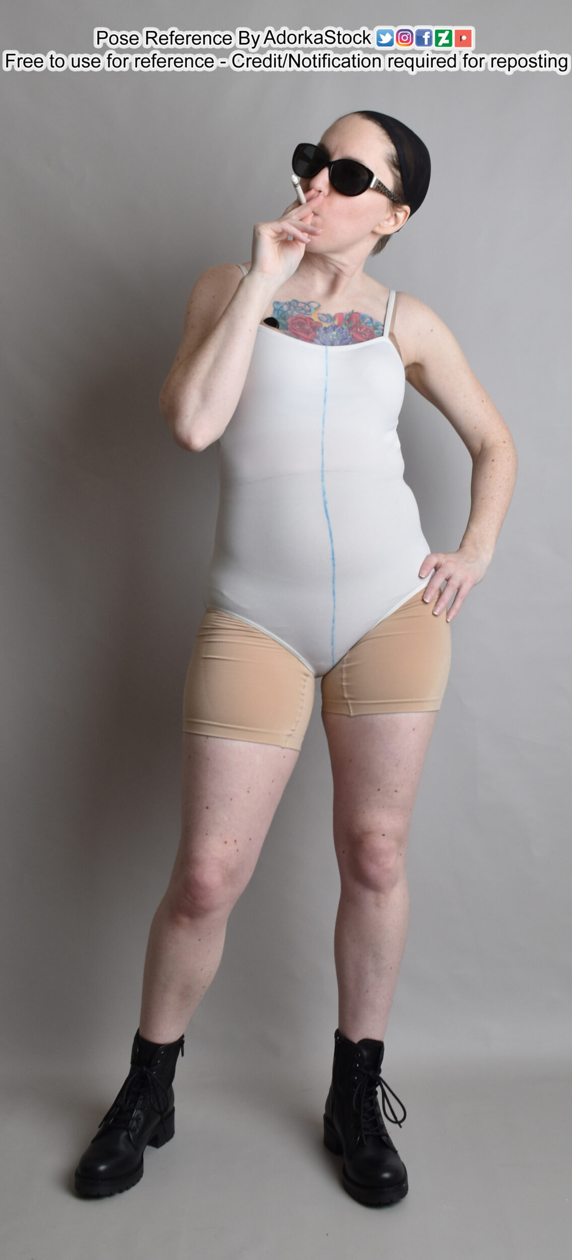 thin white female model standing in boots taking a drag on a cigarette with one hand on a hip