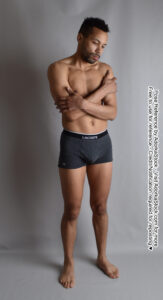 thin latino model standing and hugging himself as if cold or sad