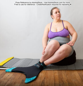 Fat, white, female pose reference model sitting on a cushion with a mermaid tail on her feet, hands resting on her legs