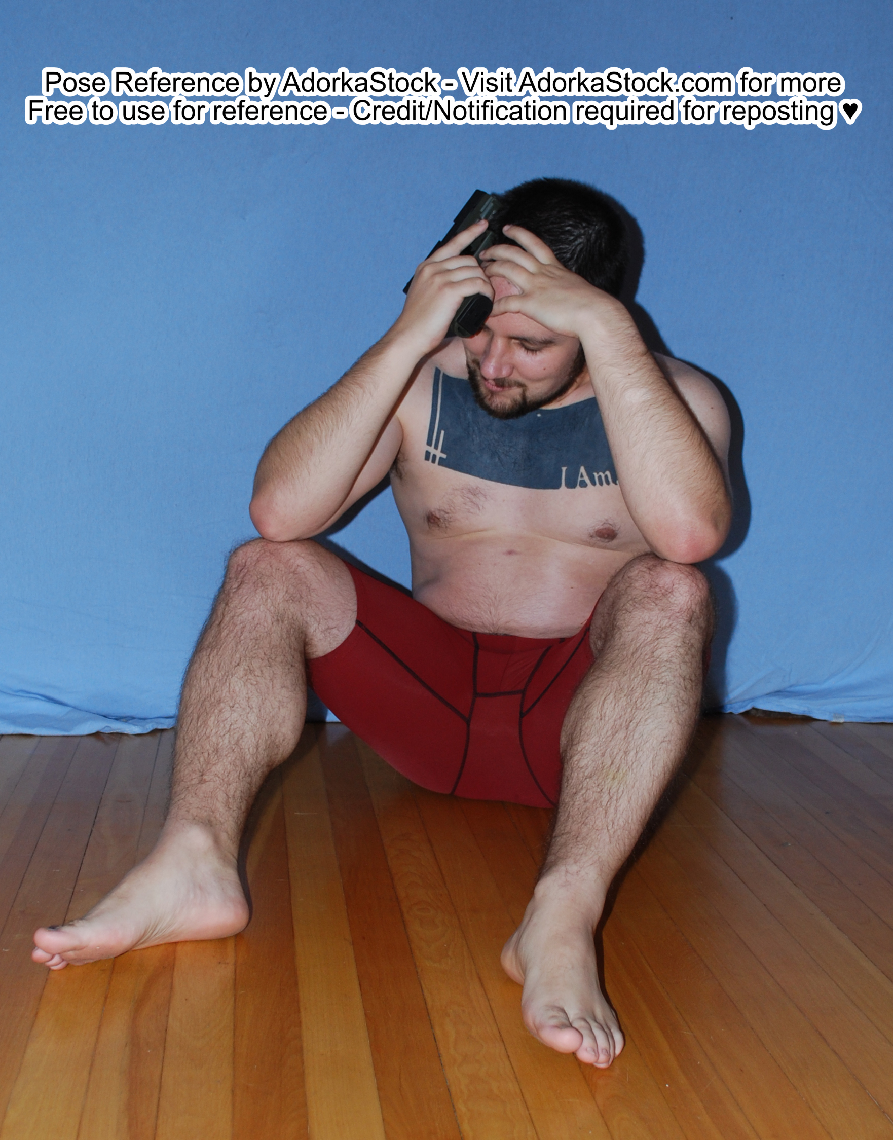 Strong male pose reference model sitting on the floor, holding a gun and holding his head looking overwhelmed