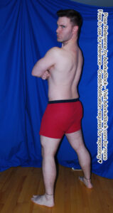 strong male model standing facing 3/4 away looking over his shoulder with his arms folded