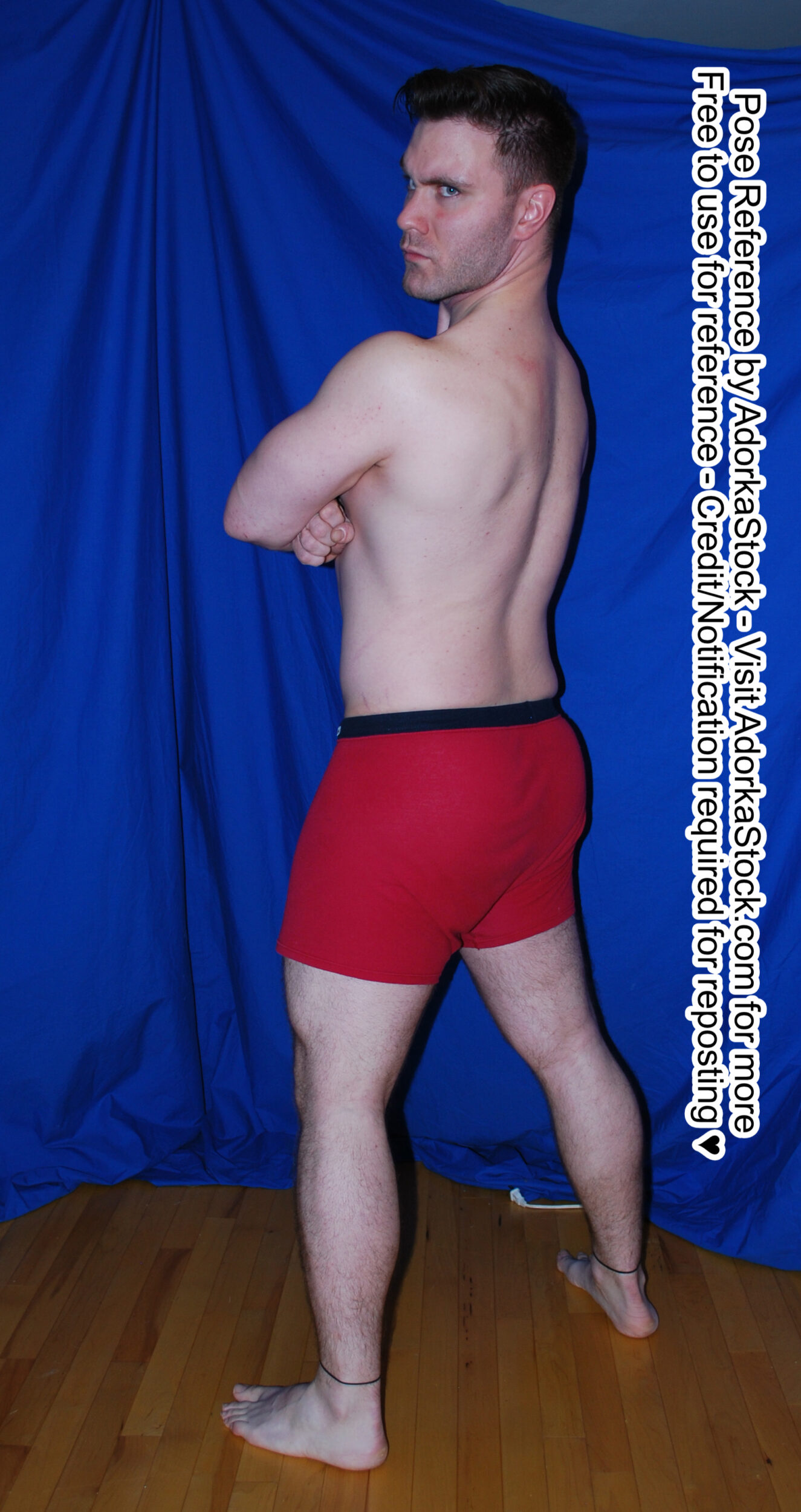 strong male model standing facing 3/4 away looking over his shoulder with his arms folded
