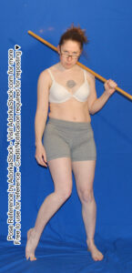 thin white female model standing with head down, staff on shoulder