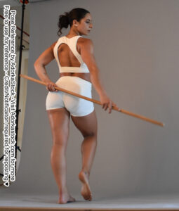 Fit Latina model facing back, looking a bit over her shoulder, holding a staff behind her