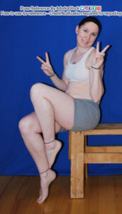Thin white female pose reference model sitting on a bench with one knee raised, hands making peace signs