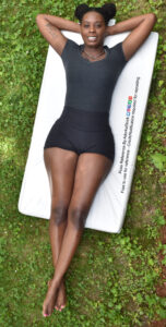 Thin, Black female model lying on the ground with her ankles crossed and arms behind her head, shot from above