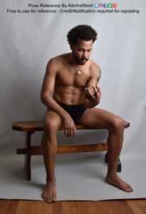 Thin Latino model sitting staring at his hand as if holding something