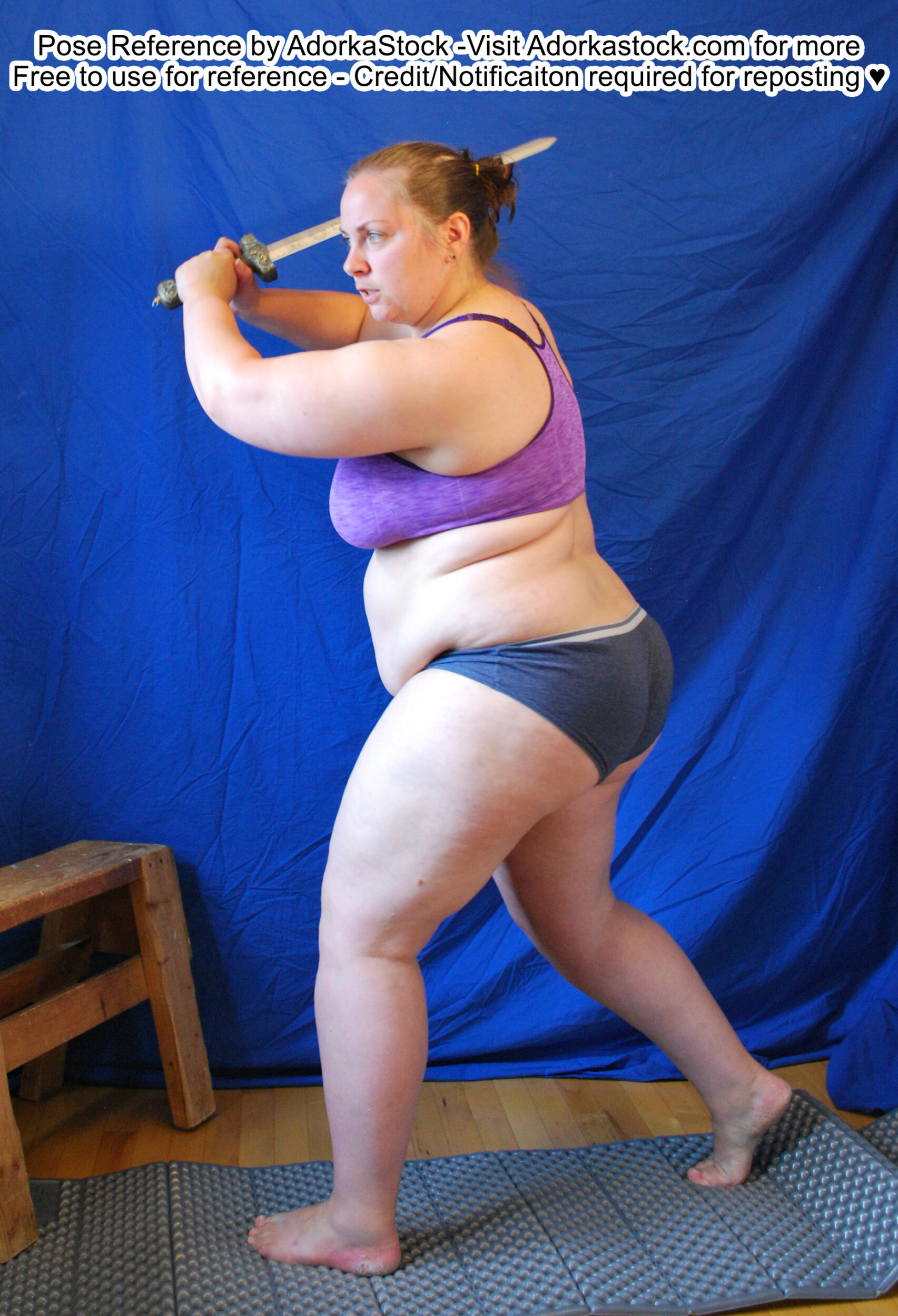 fat white female model taking a step and swinging a blade overhead