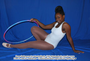 fit Black female model sitting on the ground holding a hoolahoop