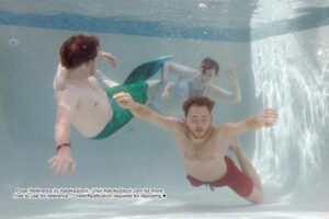 three models underwater in dynamic poses one is wearing a mermaid tail