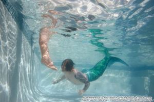 merman underwater approaching submerged toes with malicious glee
