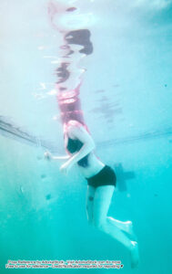 thin white female model mostly underwater with the top of her head breaking the surface