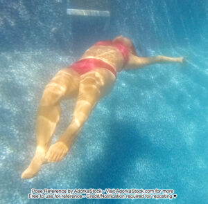thin Asian female model floating underwater feet closest to the camera head barely visible in the distance