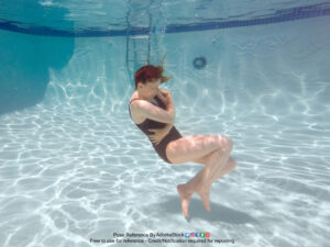thin white female model curled up underwater