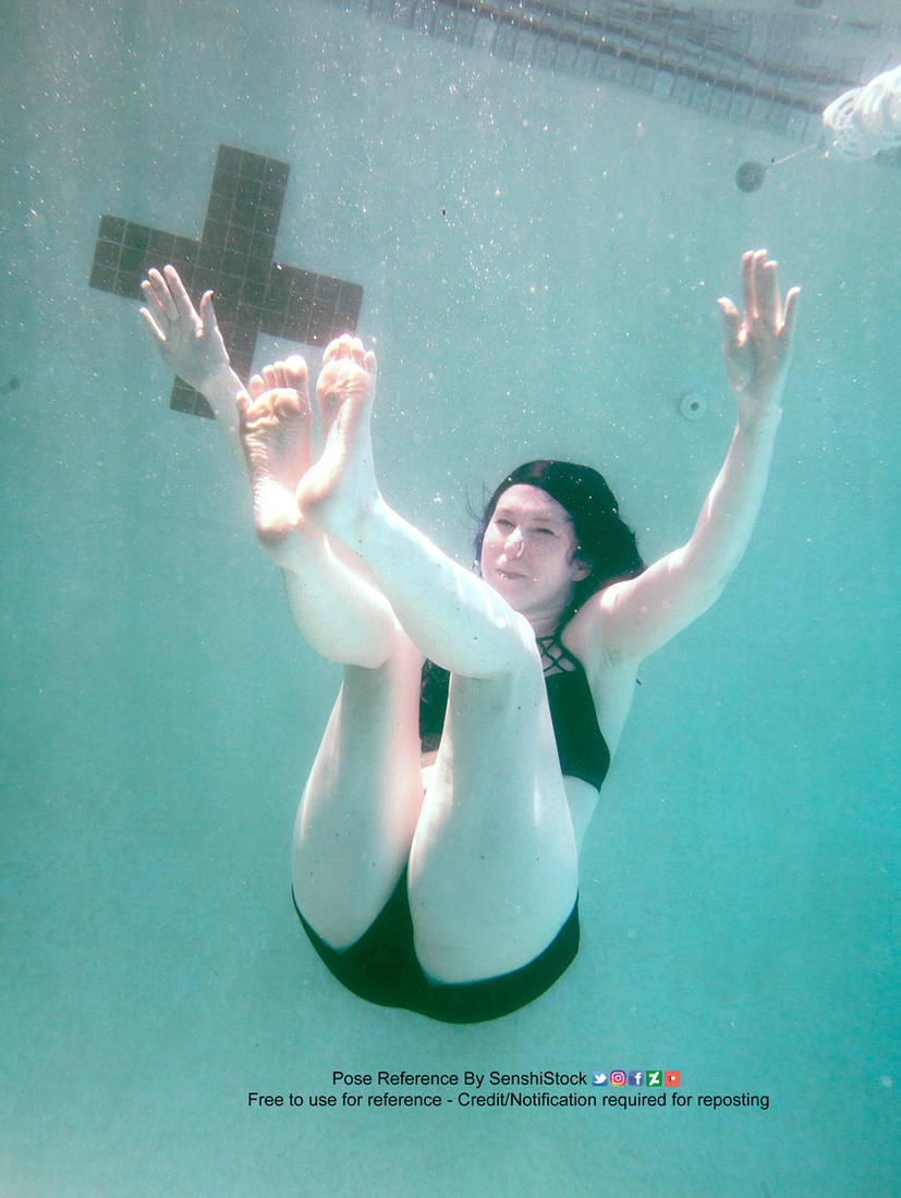A white woman wearing a black bathing suit, sinking in water, her legs and arms extended, legs towards the camera, butt going downwards.