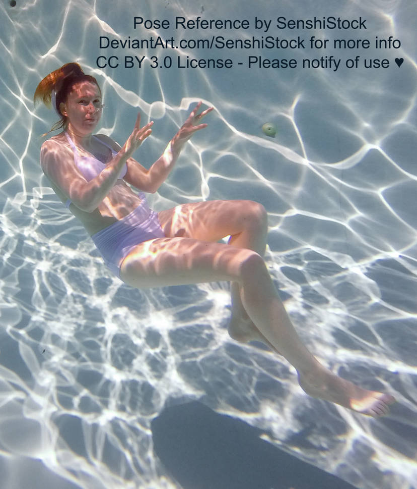 Photo of a white woman wearing a lavender two piece bathing suit floating underwater, covered in dappled light. She appears like she is sitting.