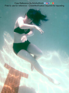 Photo of a white woman in a two piece black bathing suit, floating upward, one arm bent in front of her, one leg bent up, the other extended.