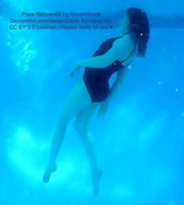 A white woman in a one piece black swimsuit swimming upward, legs outstretched towards the bottom of the photo.