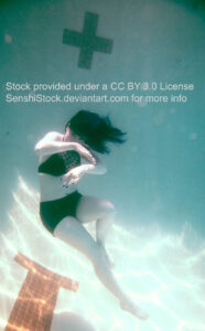 A white woman wearing a two piece black bathing suit, angled underwater, one knee bent, the other extended, both arms in front of her.