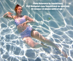 Photo of a white woman wearing a lavender two piece bathing suit floating underwater, covered in dappled light. She appears like she is twirling, one leg extended, the other knee bent.