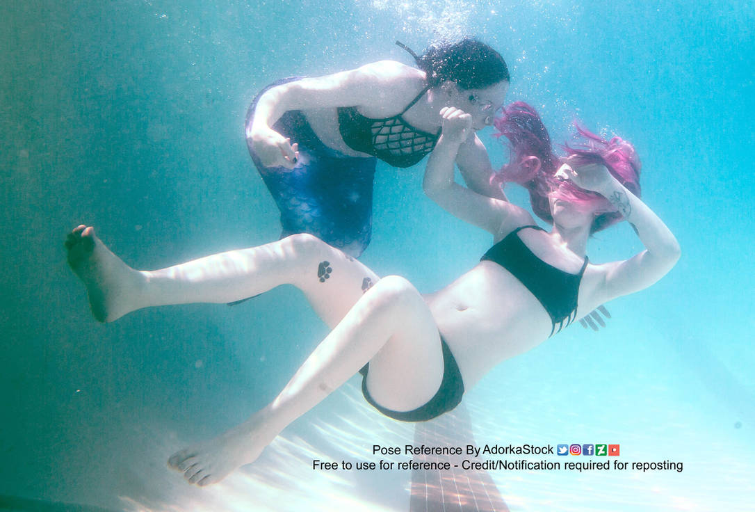 Two white women, one of which appears to be falling backwards and "drowning" (on the right) and the woman on the left is wearing a mermaid tail, trying to catch her.
