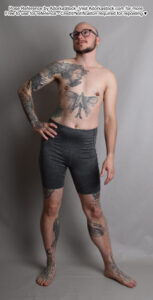 Thin, white, male model standing with one hand on his hip the other hanging beside him