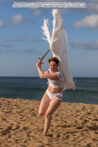 thin white female model running at the camera with a sword wearing huge wings