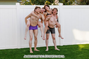 Two male models carrying female models in piggy backs, the girls on their backs are leaning towards each other