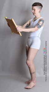 nonbinary model standing with a scroll open as if reading