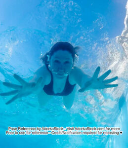 underwater model swimming towards the camera below her reaching out with two hands