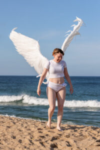 winged figure model walking on the beach