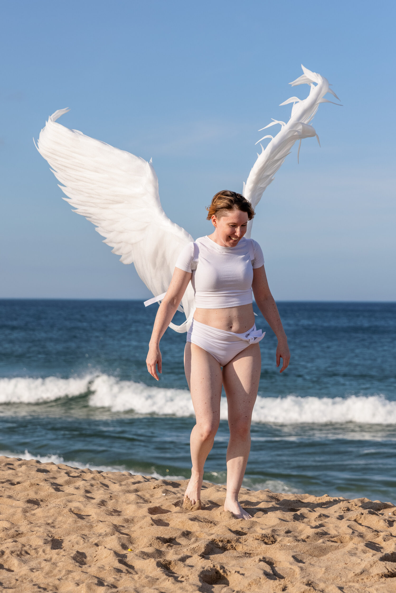 winged figure model walking on the beach