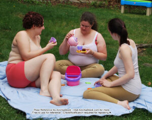 three models sitting together on a sheet outside having a tiny tea party