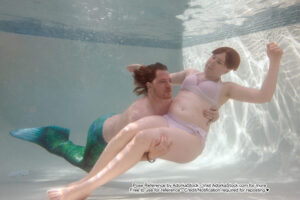 Merman scooping up a underwater woman into his arms
