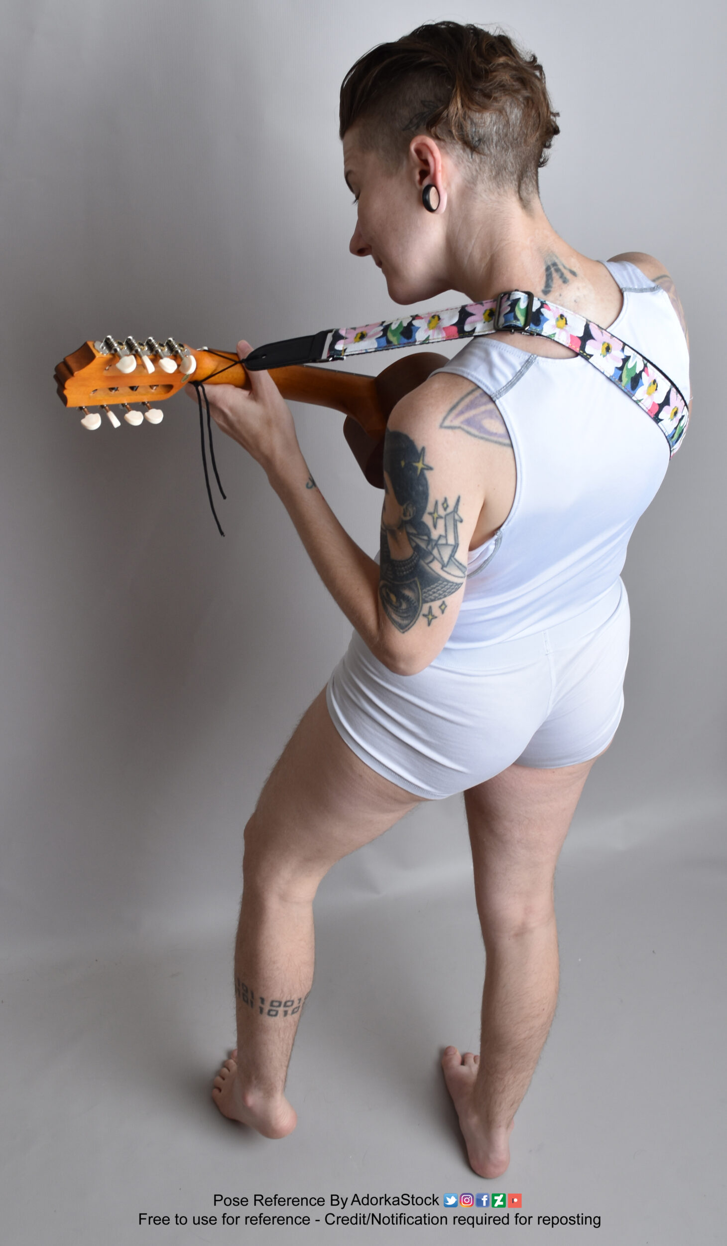 Thin white nonbinary model from a high perspective facing away holding a ukulele