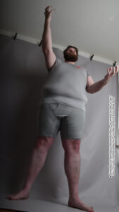 a white fat male model reaching into the air dramatically and the photo is from a low angle making him look like a giant