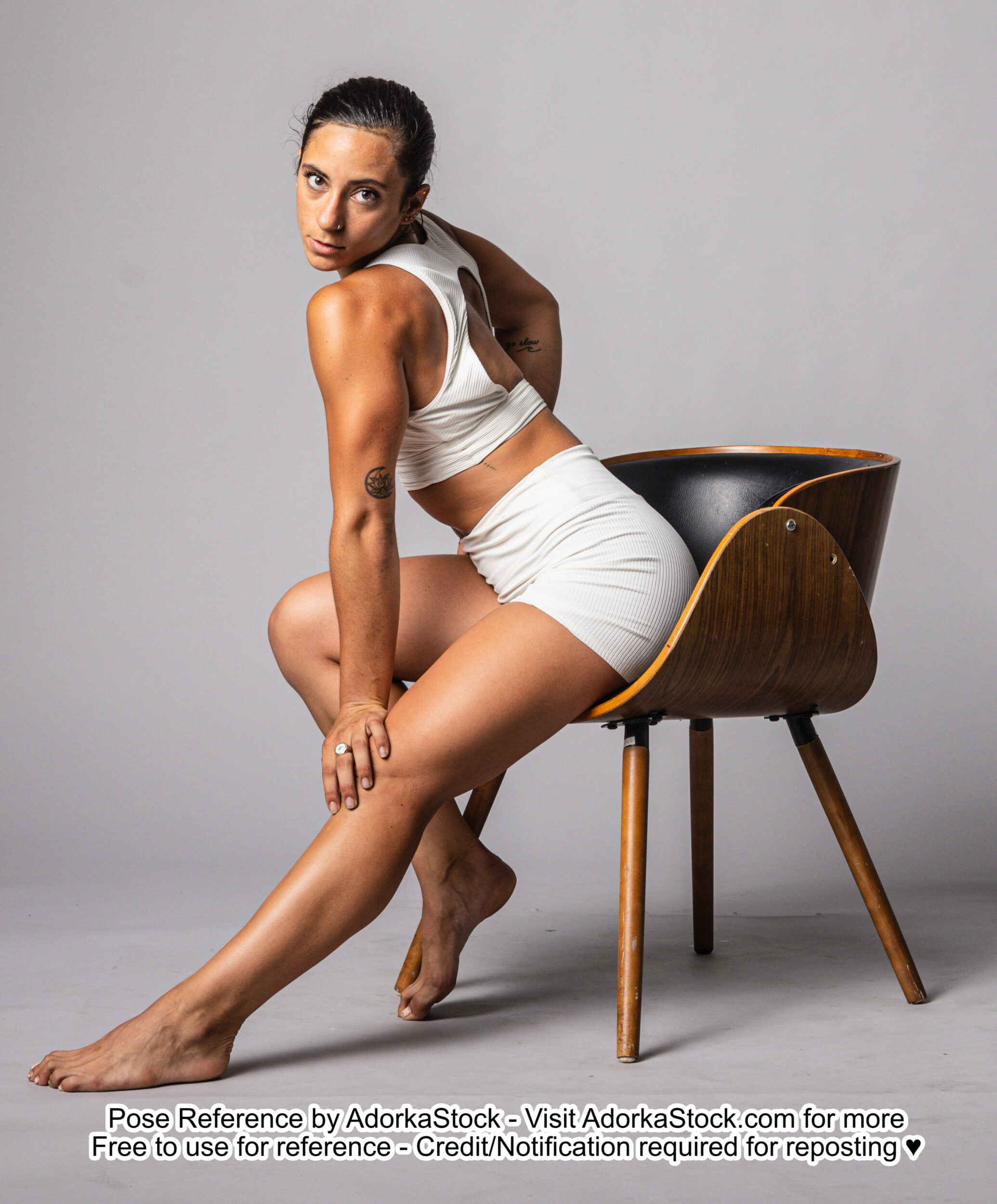 fit Latina model sitting in a chair reaching down to put one hand on her knee