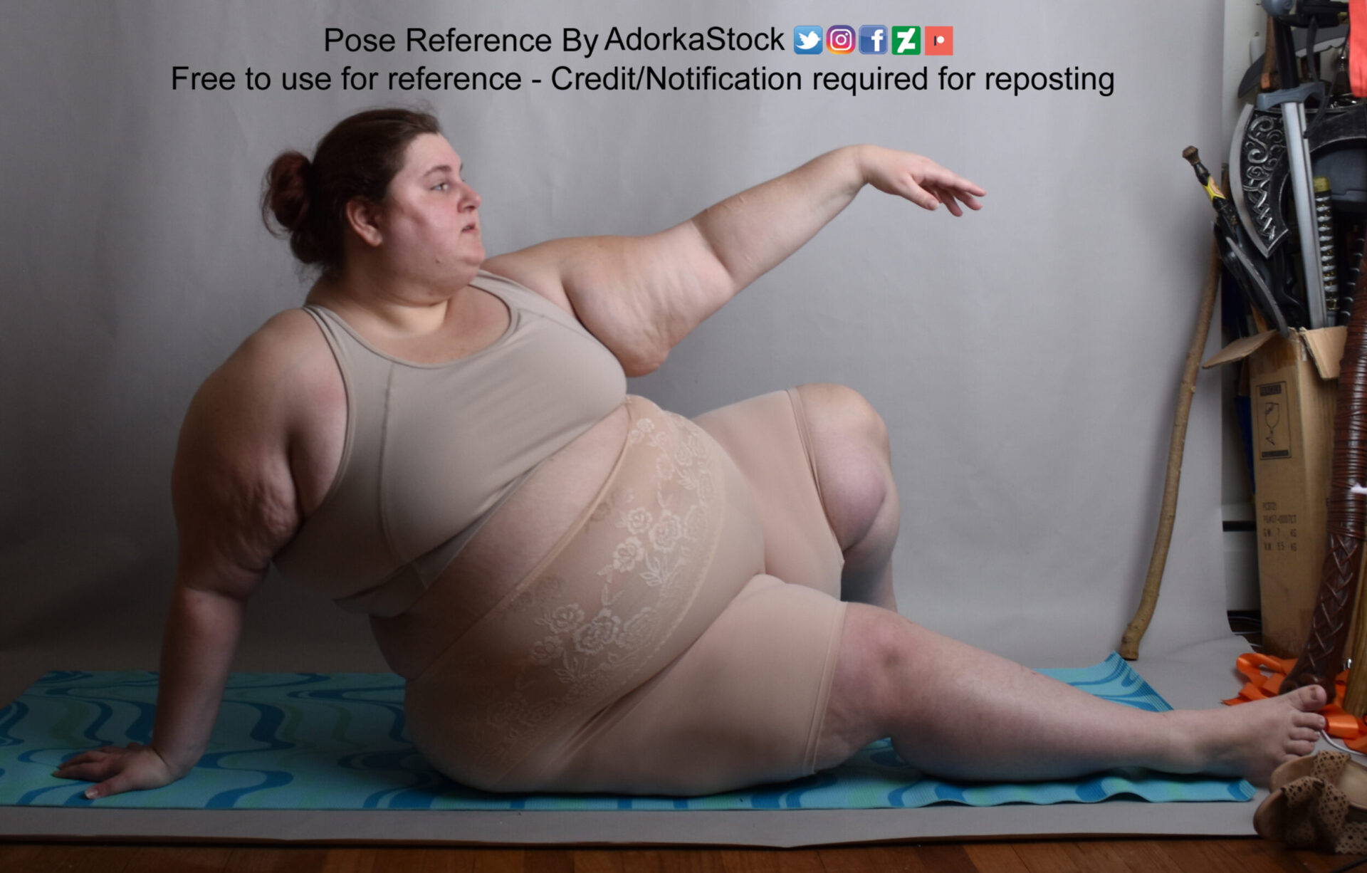 fat white female model sitting on the floor, supported by one arm while the other reaches out in profile