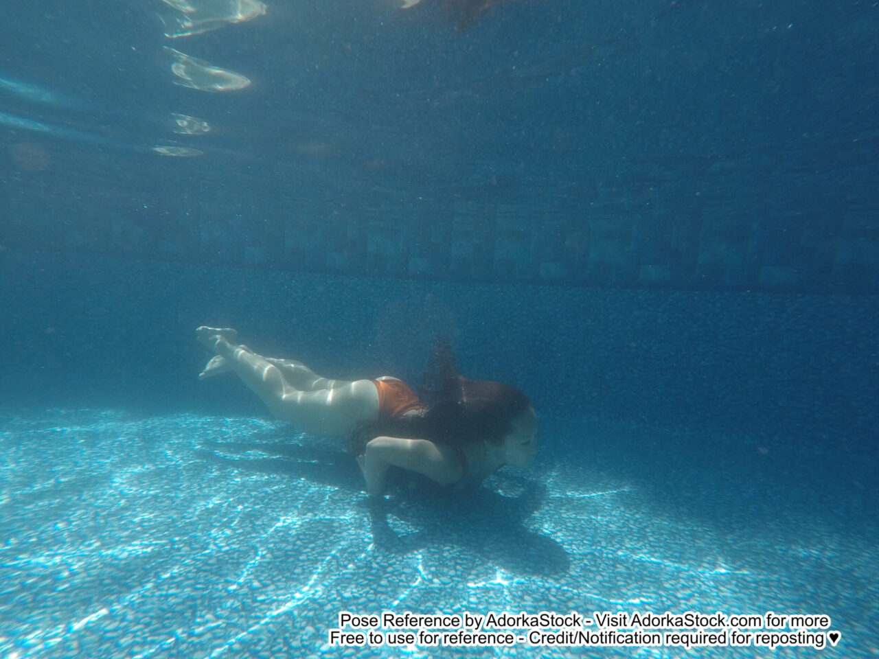thin female Asian model swimming near a pool's floor