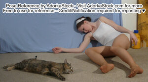 White woman lying collapsed against a wall, a cat spread out beside her.
